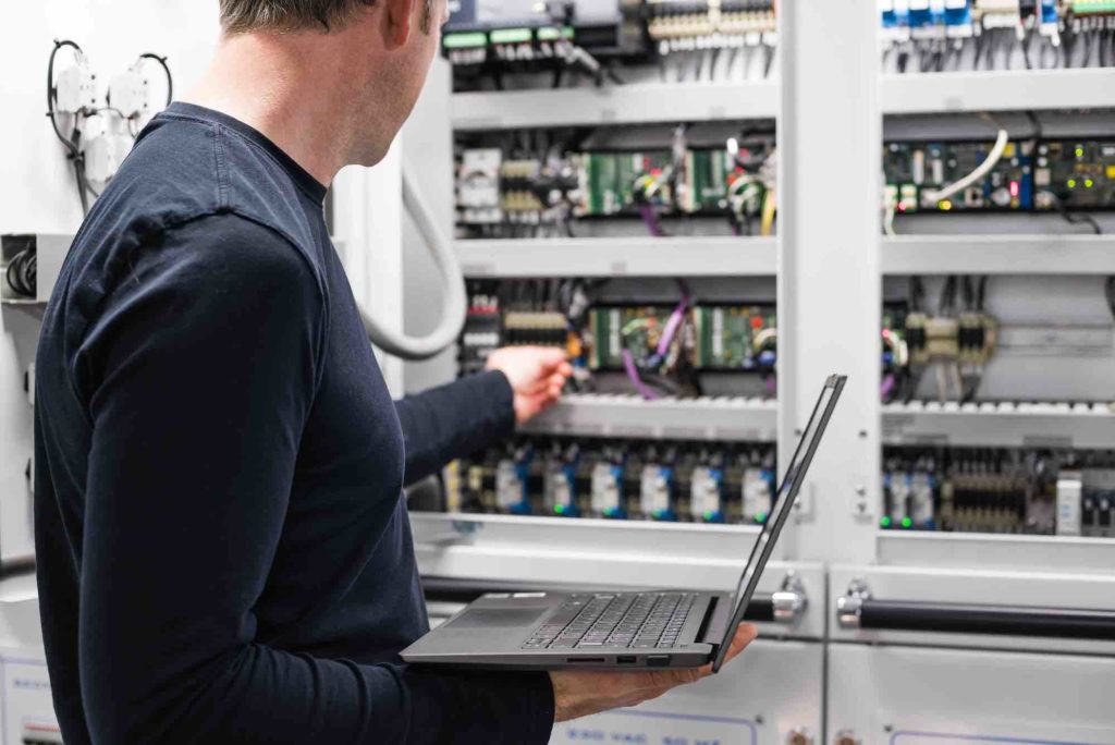 Caucasian Male Superyacht Engineer - ETO working on the engine room control panel with laptop