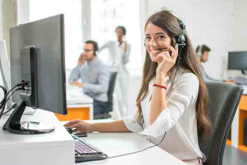 Young friendly operator woman agent with headsets working in a call centre.