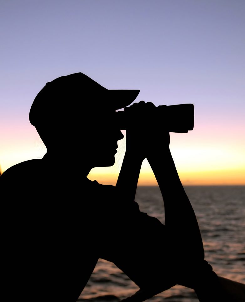 silhouette of a ship captain looking through binoculars