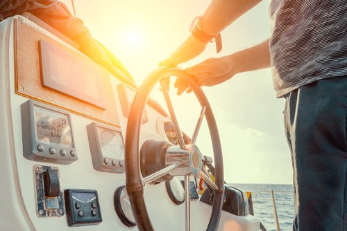 Hand of man on the steering wheel sailboat. Hands on the sailboat's steering wheel. Man's Hands with clocks Steering Wheel Of Yacht. Close-up of a man's hands on the yacht steering wheel. Helm yacht