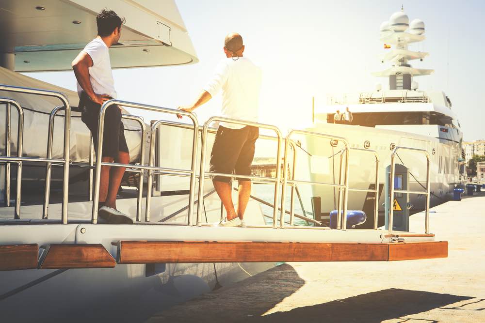 Yacht crew standing on the gate ramp at port.