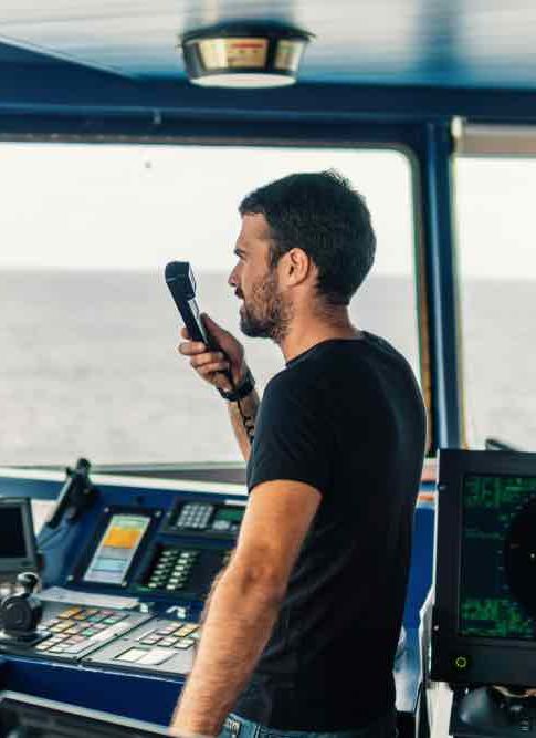 Marine navigational officer is reporting by VHF radio during navigation watch. Bridge GMDSS watch