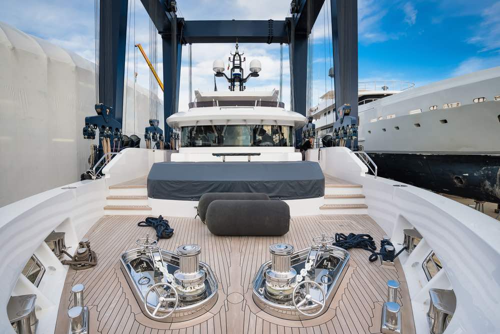 Superyacht being hauled out for shipyard period with travel lift crane with blue sky